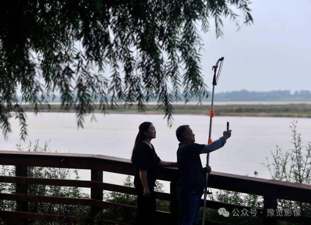 黄平安和同事工作之余，在黄河边用手机拍摄黄河美景。在黄河滩地公园郁
