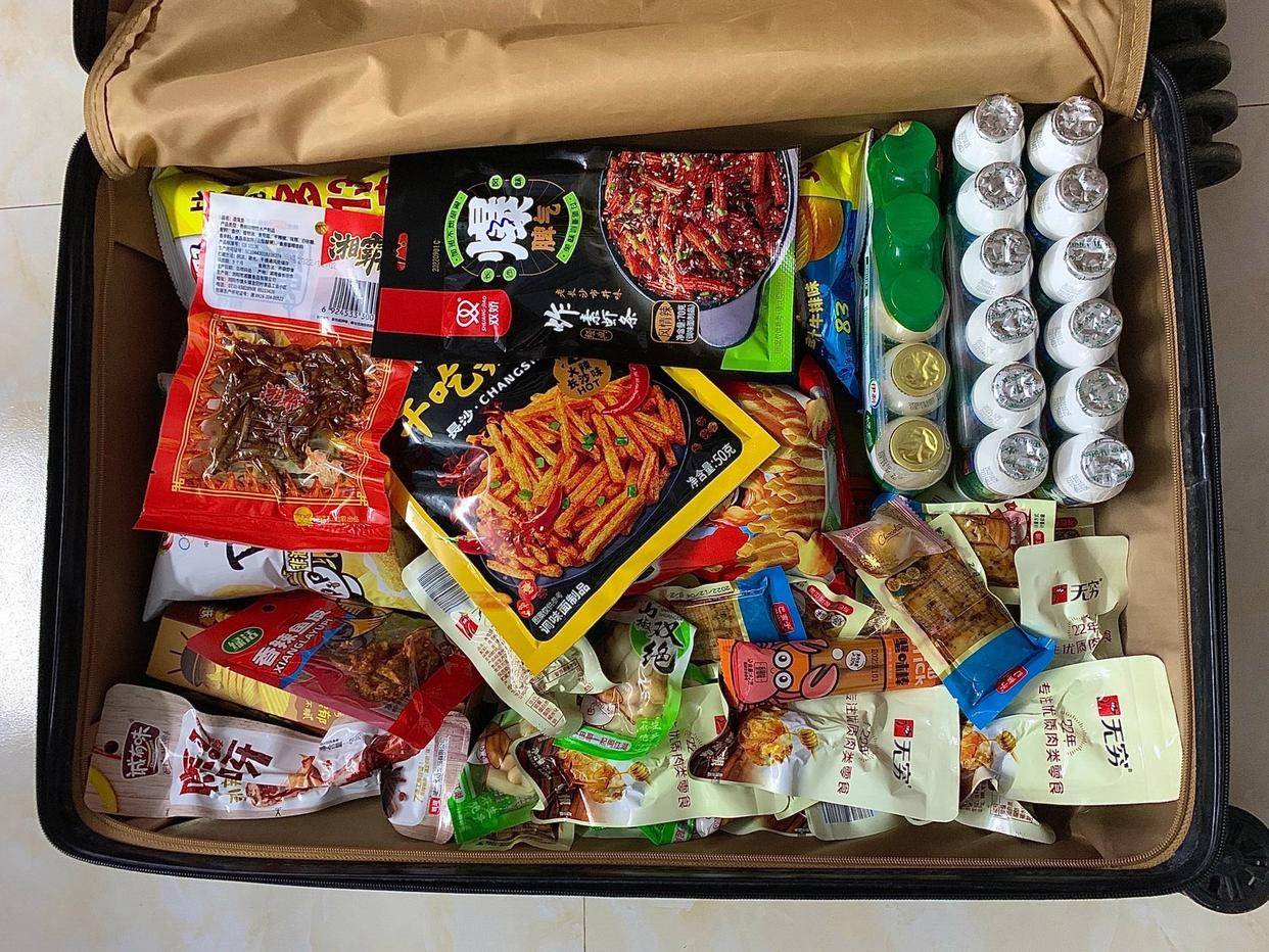 来自全国各地的大学生晒出自己行李,里面装满了各种零食小吃,各种家乡