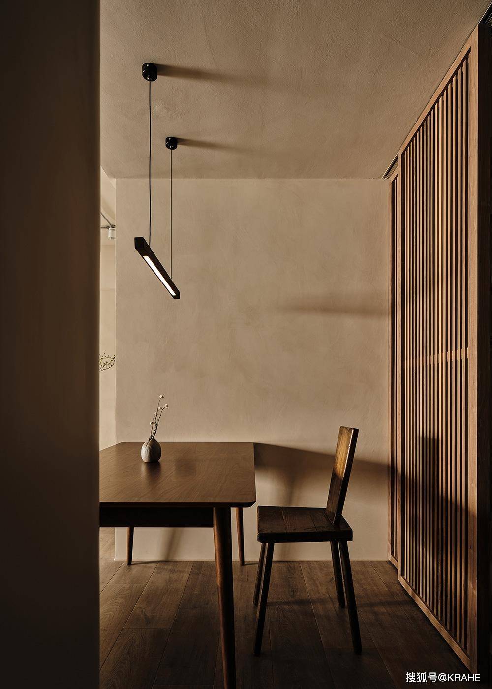 一款简约的木质吊灯垂挂下来,与格柵门片形成了有趣的组合,木格柵既