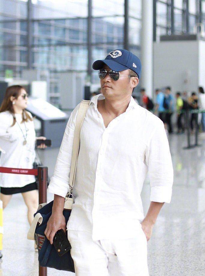 原创45岁吴京现身机场,白衣配"马蹄鞋"混搭出时髦感,美黑肤色抢镜