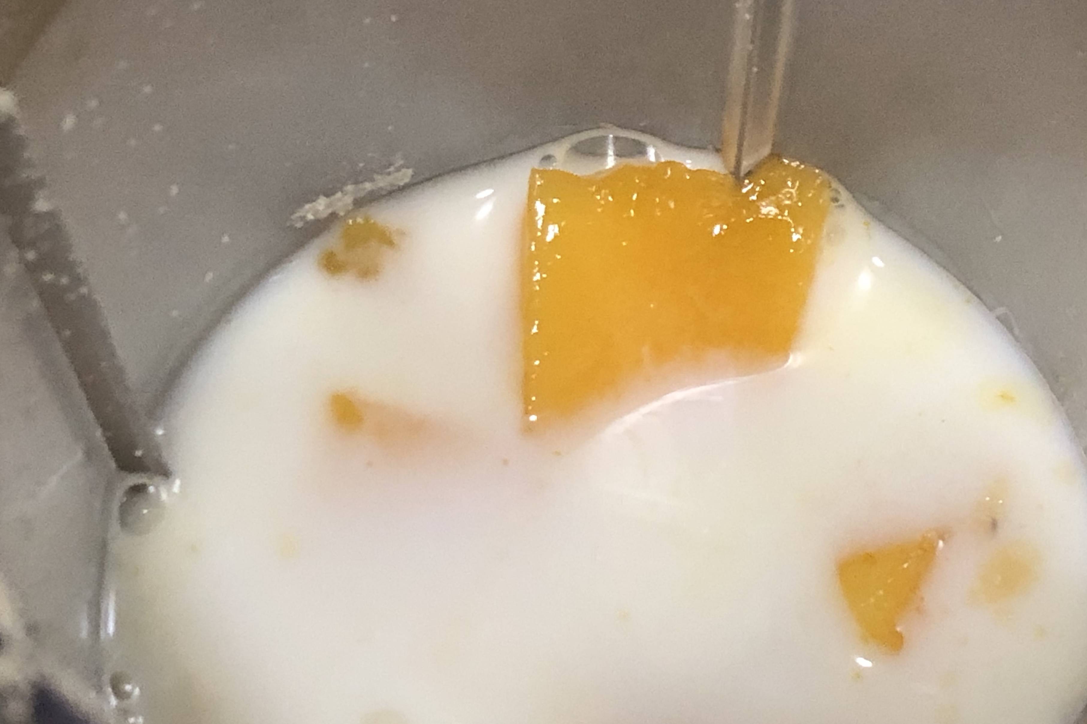 8,接下来,把吉利丁溶液和刚才的芒果糊放到一起,用手动打蛋器搅拌均匀