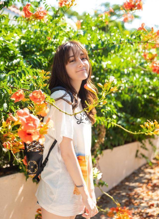 双手抓住双肩背包肩带的迪丽热巴,像不像在等校车去上学的邻家学妹呢?