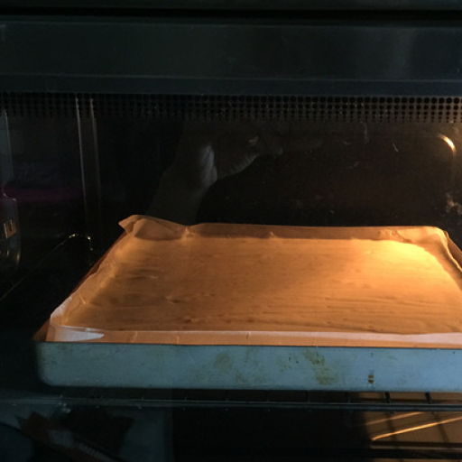 第7步,将蛋糕糊倒进铺有油纸的烤盘中,震出大气泡,用两根牙签不规则