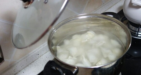 锅里热水沸腾时,放入几滴花生油,把制作好的水饺一个个放入.