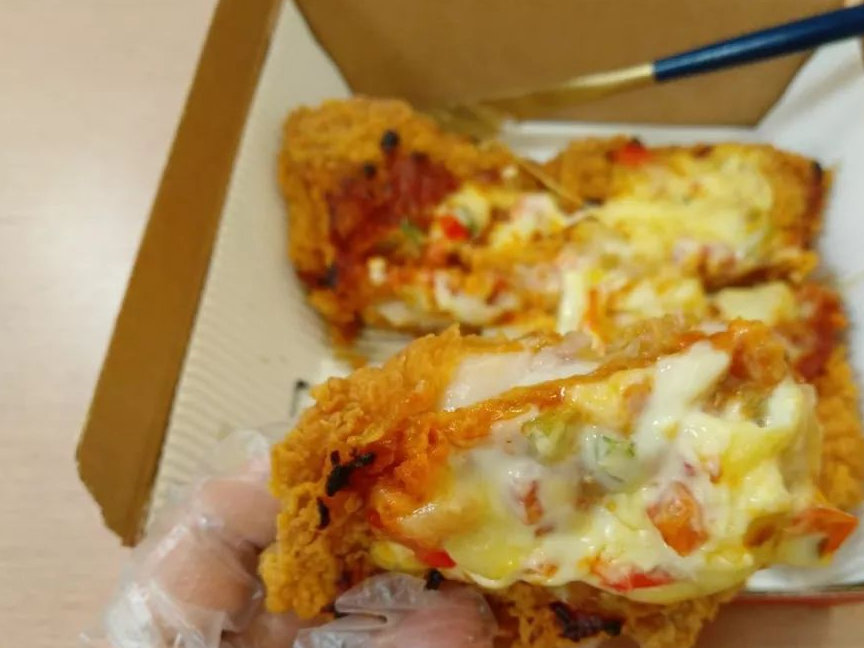 饼底是炸鸡腿排,之上是的红色固体类似被烤过的番茄酱,最上则是芝士和