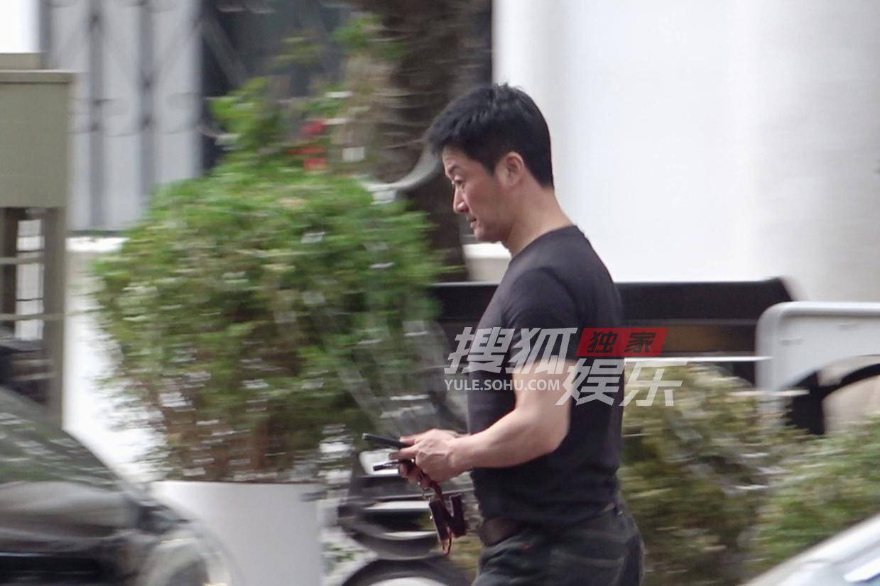 吴京清爽短发造型曝光 专注手机行色匆匆显事业心