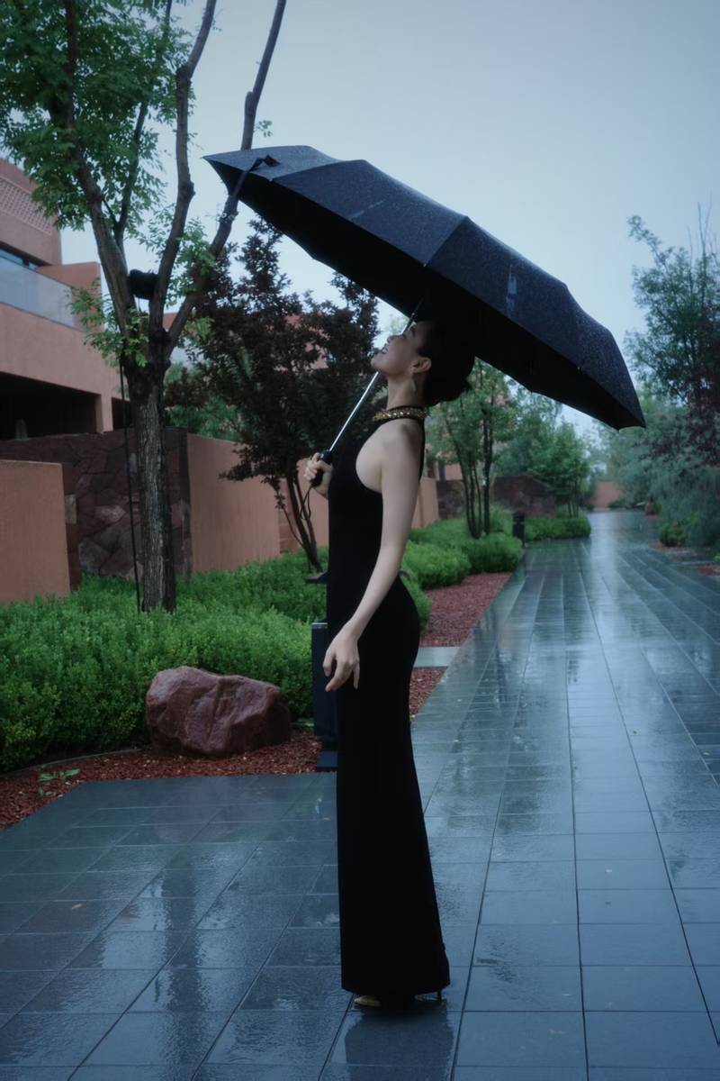倪妮穿挂脖裙身材曼妙 撑黑伞漫步雨中尽显故事感