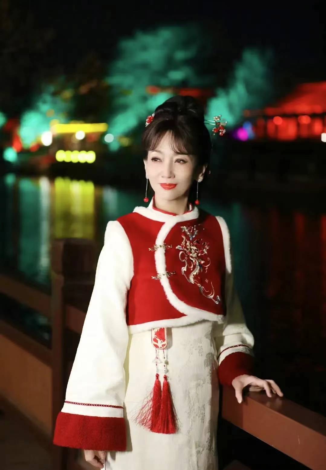 照片中的赵雅芝,身着红色中国风马甲和白色旗袍,不仅展现了浓厚的节日