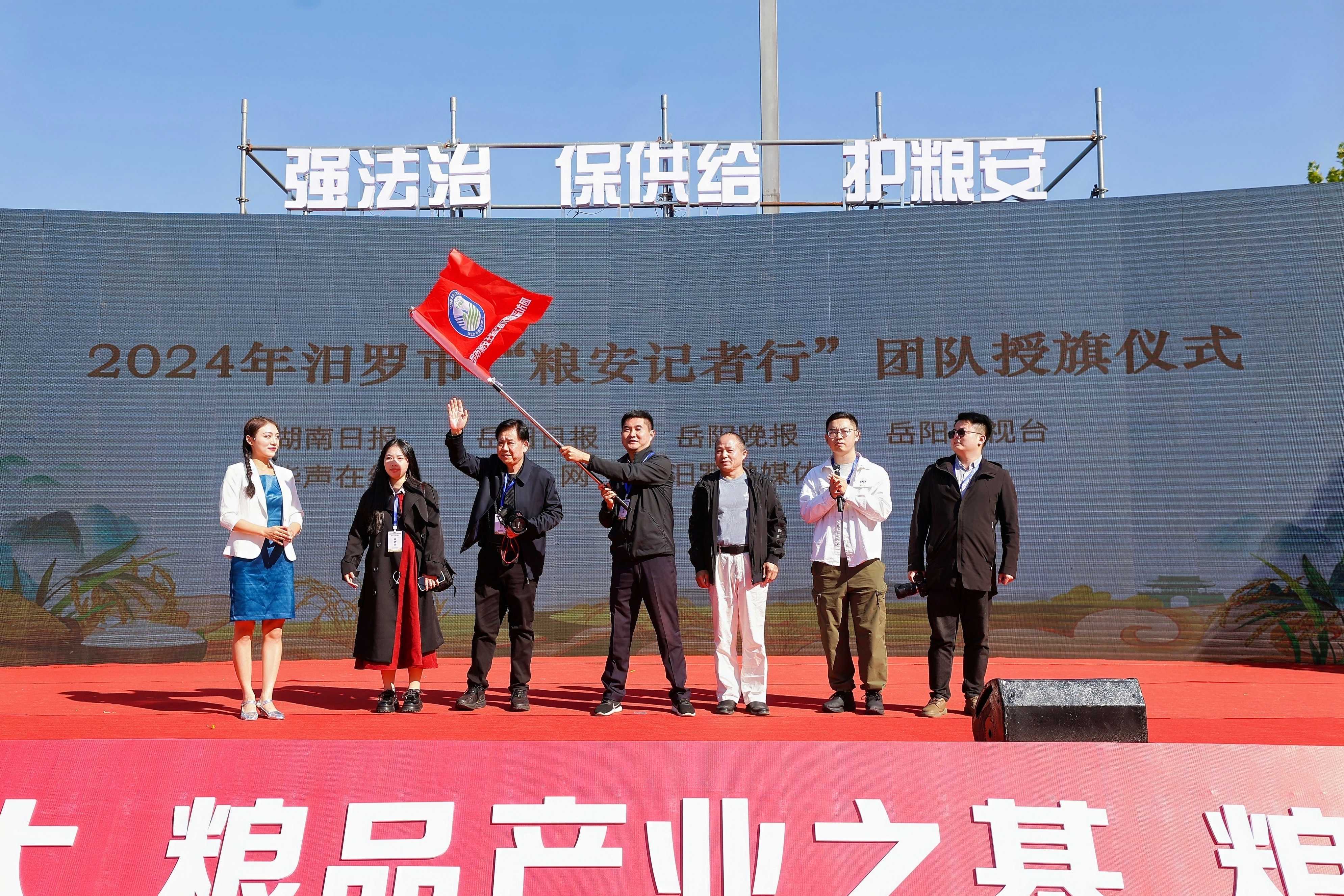 岳阳新媒体协会副会长徐典波从汨罗市商务粮食局副局长朱再文手中接过