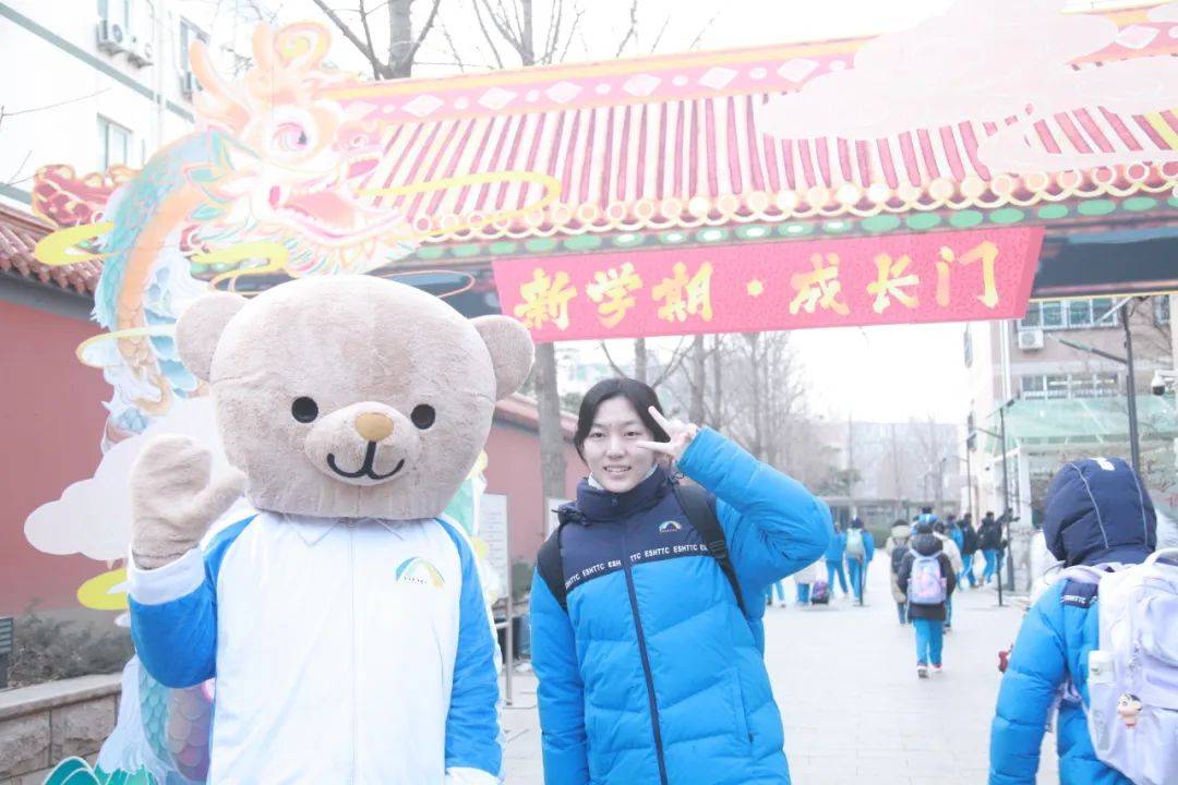 校门前,学生们像成群的鲤鱼一样跃过自己设计的"成长门",与校服熊拍照