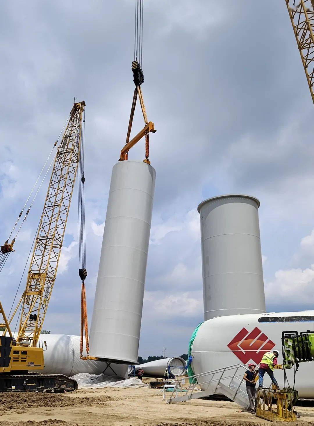 图为风机塔架吊装现场风机塔架是支撑风力发电机的主要机械部件,使用