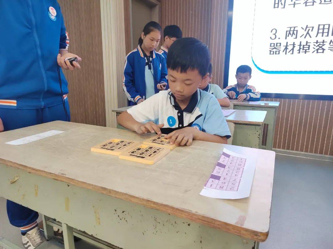 只见,一个个的华容道在三年级孩子们手中不停变换,他们争分夺秒,扎步
