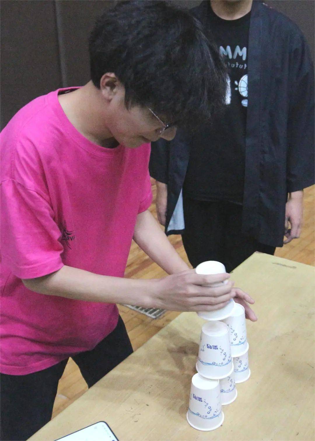 第一个游戏是"纸杯叠叠高",同学们需要将桌子上纸杯通过接力的方式