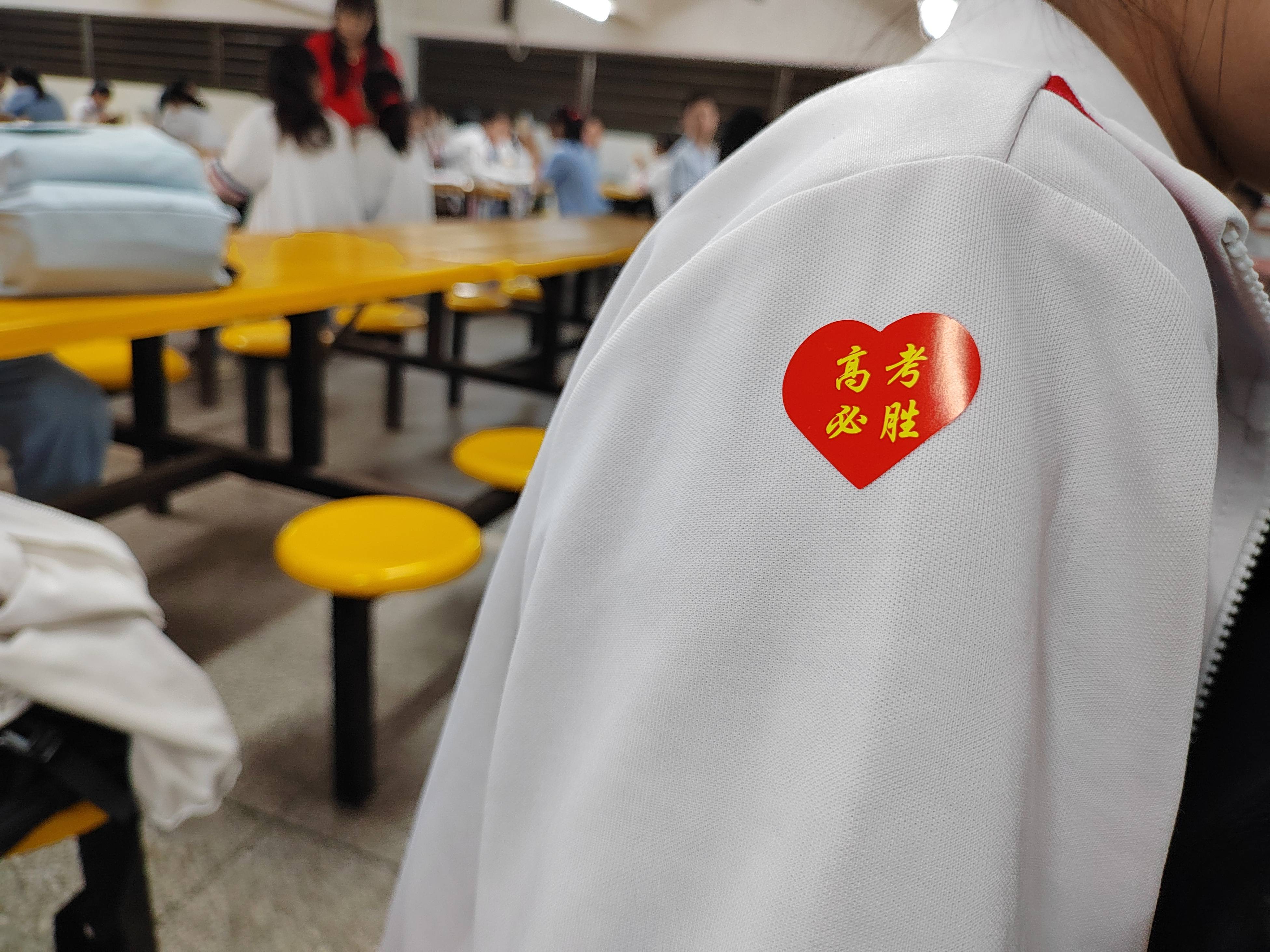 汕头市华侨中学里,身着红衣的带考老师在候考考生手臂上贴上"高考必胜