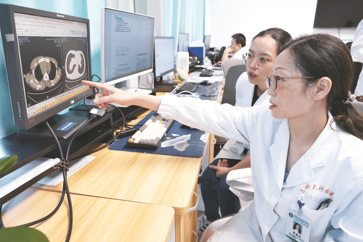 谭晓虹（右）与同事讨论病例。谭晓虹（右）询问患者身体状况。本报记者