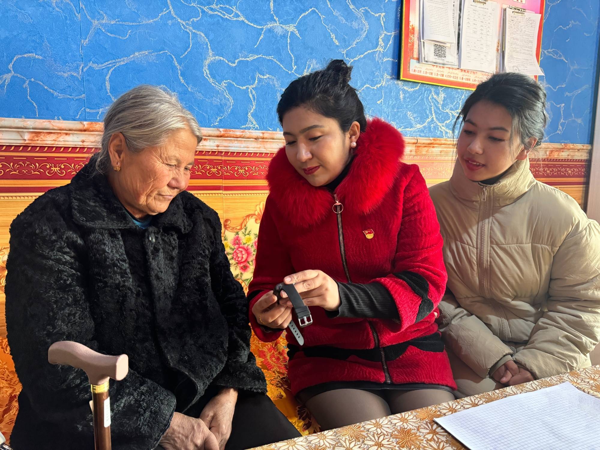 村,民政办负责人正在给村民阿依汗·斯迪克讲解智能手环的使用方式