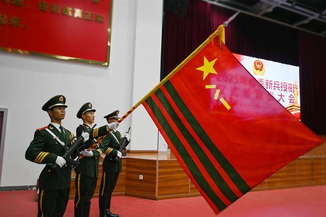 随着口令响起,三名擎旗手高举武警部队旗,迈着铿锵有力的步伐走过国旗