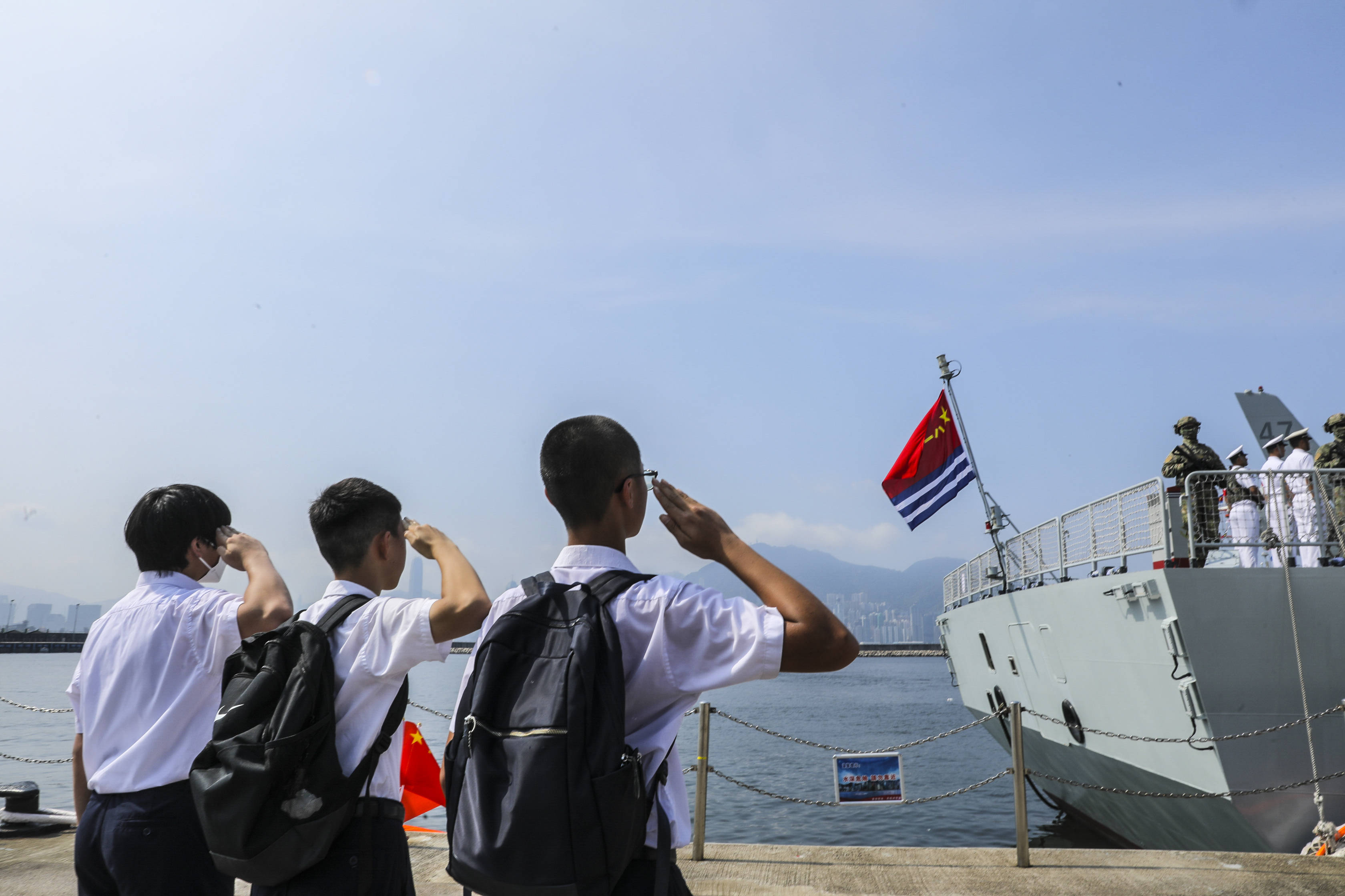 三名香港福建中学的学生向悬挂在舰尾的海军军旗敬礼